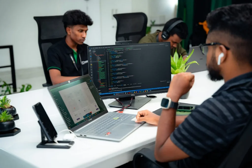 Website maintenance packages – W3Inventor software engineers coding a React-based web application on dual screens inside the Tech Lab